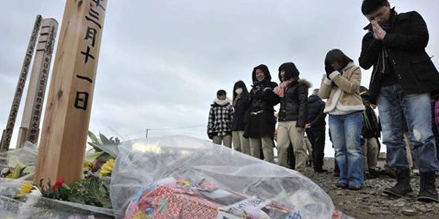 Mar. 11, 2012: People offer prayers to mourn the victims of the March 11, 2011 earthquake and tsunami on a hill in Natori, Miyagi prefecture, Japan.