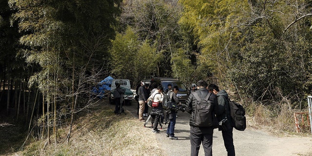 Journalists gather near the site where a body part believed to be of a missing woman was found in Osaka, western Japan Monday, Feb. 26, 2018.