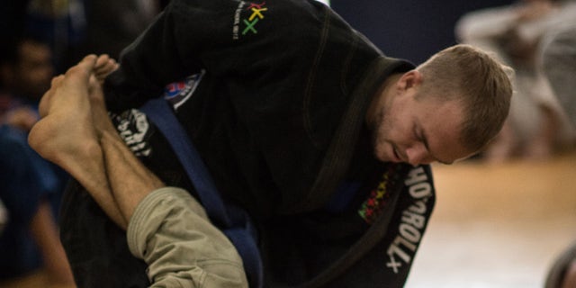 TO GO WITH AFP STORY by Sebastian SmithNew Zealander Jason Lee (top) practices jiu-jitsu in Rio de Janeiro, Brazil, on September 14, 2015. Once restricted almost entirely to the Latin American country, Brazilian jiu-jitsu is one of the world's fastest-growing forms of unarmed combat, credited with igniting the mixed martial arts or MMA cage fighting phenomenon, and popular from the United States to the Middle East and Asia. AFP PHOTO / CHRISTOPHE SIMON (Photo credit should read CHRISTOPHE SIMON/AFP/Getty Images)