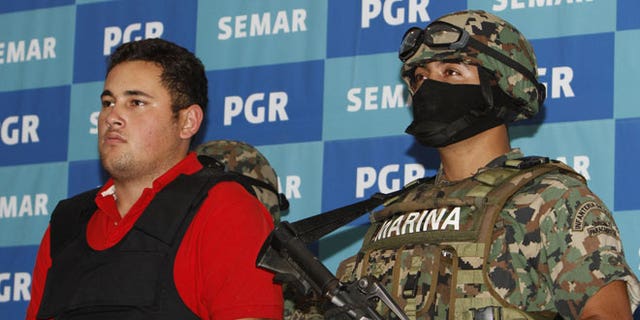 June 21, 2012: A Mexican marine escorts Jesus Alfredo Guzman Salazar, left, during his presentation to the media in Mexico City.