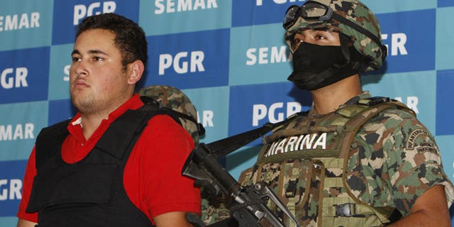 June 21, 2012: A Mexican marine escorts Jesus Alfredo Guzman Salazar, left, during his presentation to the media in Mexico City.