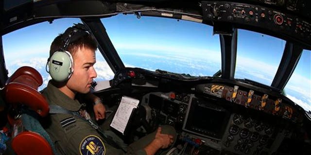 In this Wednesday, March 26, 2014 photo, Flight Lt. Russell Adams looks out from the cockpit on board a Royal Australian Air Force AP-3C Orion, during a search for the missing Malaysia Airlines Flight 370 in the southern Indian Ocean. A French satellite scanning the Indian Ocean for remnants of the missing jetliner found a possible plane debris field containing 122 objects, a top Malaysian official said Wednesday, calling it "the most credible lead that we have." (AP Photo/Paul Kane, Pool)