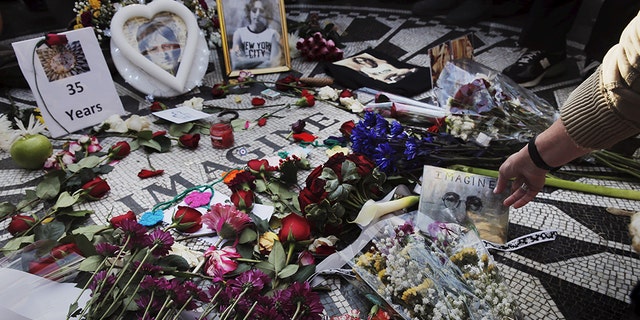 A woman sets a photograph down as she joins fans of former Beatle John Lennon who have gathered at the Imagine mosaic in the Strawberry Fields section of New York's Central Park to mark the 35th anniversary of his death, in New York on Dec. 8, 2015.