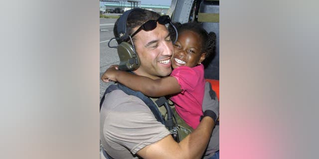 Air Force Reserve Master Sgt. Mike Maroney hugs 3-year-old he rescued in aftermath of Hurricane Katrina in 2005. (Credit: Air Force)