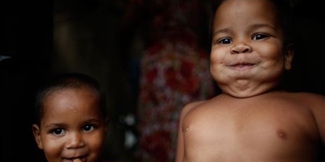 In this Feb. 8, 2015 photo, Miguel, 5, right, and Micael, 2, stand in their family's makeshift tent at a Homeless Workers Movement camp in Brasilia, Brazil. (AP Photo/Eraldo Peres)