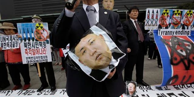 South Korean protesters hold a picture of North Korean leader Kim Jong Un during an anti-North Korea rally against recent missile launches and provocative acts, on the birthday of its founder, Kim Il Sung, in Seoul, South Korea, Tuesday, April 15, 2014. The banners read: "Denounce North Korea's dictatorship." (AP Photo/Lee Jin-man)