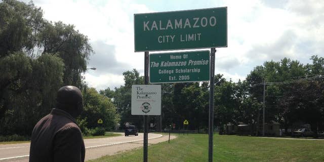 Kalamazoo Mayor Bobby Hopewell looks at a recently unveiled city limit sign honoring the Kalamazoo Promise,  Friday, Aug. 14, 2015, in Kalamazoo, Mich. (AP Photo/ Mike Householder)