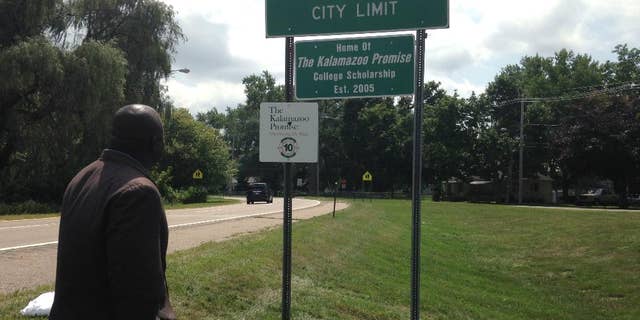 Kalamazoo Mayor Bobby Hopewell looks at a recently unveiled city limit sign honoring the Kalamazoo Promise,  Friday, Aug. 14, 2015, in Kalamazoo, Mich. (AP Photo/ Mike Householder)