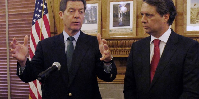 FILE - In this Sept. 11, 2014 file photograph, Kansas Gov. Sam Brownback, left, and Lt. Gov. Jeff Colyer speak at the Statehouse in Topeka. (AP Photo/John Hanna, File)