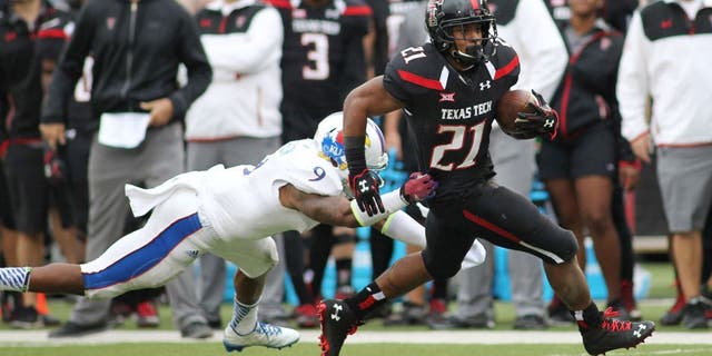 Oct 18, 2014; Lubbock, TX, USA; Kansas Jayhawks safety Fish Smithson (9) attempts to tackle Texas Tech Red Raiders running back DeAndre Washington (21) in the second half at Jones AT&T Stadium. Mandatory Credit: Michael C. Johnson-USA TODAY Sports
