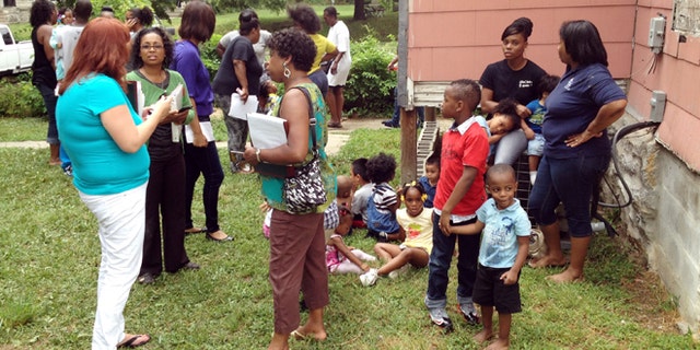 July 30, 2013: Dena Washington, middle of 3 women on left, director of the Christian Academy Child Care, stands behind a house near the center with children waiting to be picked up after a car crashed into the day care in Kansas City, Mo.