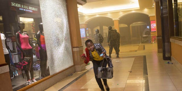 FILE - In this Saturday, Sept. 21, 2013 file photo, a woman who had been hiding during the gun battle runs for cover after armed police enter the Westgate Mall in Nairobi, Kenya, after gunmen threw grenades and opened fire at the upscale mall. (AP Photo)
