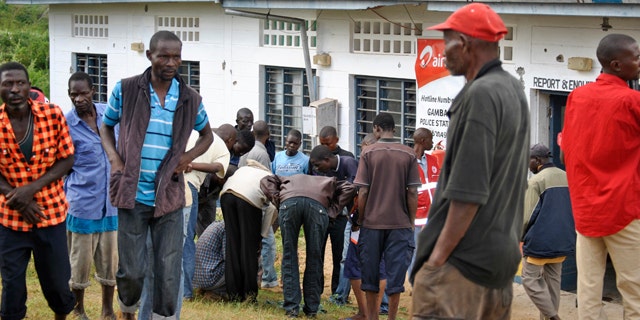 July 6, 2014: People watch the site where gunmen attacked outside the Gamba police station in Gamba, Kenya. (AP Photo)