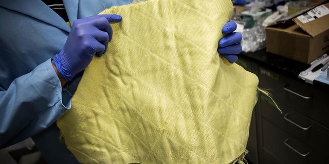 Siu On Tung, Macromolecular Science & Engineering doctoral student, shows a kevlar cloth.