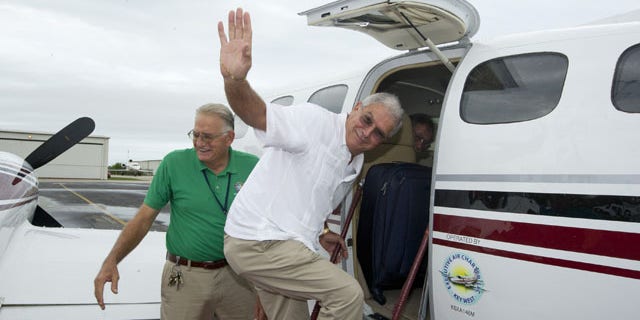 In this photo provided by the Florida Keys News Bureau, Key West December 30, 2013: Mayor Craig Cates, right, waves goodbye as he boards a chartered aircraft at Key West International Airport that flew to Havana, Cuba. The trip was the first legal commercial passenger flight from Key West to Cuba in more than 50 years and carried passengers who will remain until Jan. 3, 2014. (AP/Florida News Bureau)