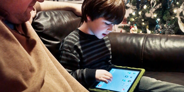 Adam Cohen watches his son Mark, 5, use a tablet at his New York home on December 3, 2013.