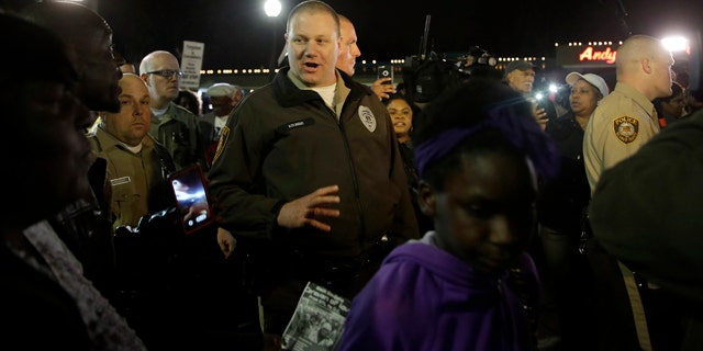 March 12, 2015: Members of the St. Louis County Police Department walk through a crowd of protesters trying to move them out of the street in front of the Ferguson Police Department. (AP Photo/Jeff Roberson)