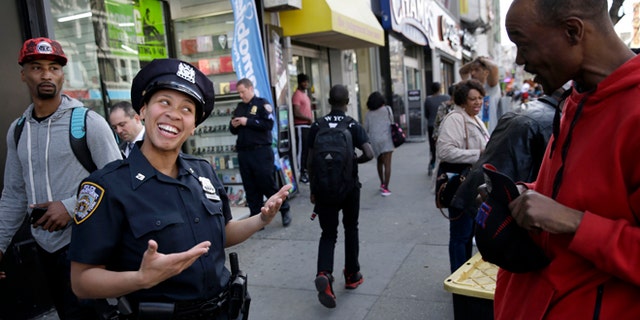Police officer Lanora Moore talks with a man on 125th Street in the Harlem section of New York, Wednesday, April 29, 2015. (AP Photo/Seth Wenig)