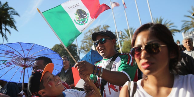 LOS ANGELES, CA - OCTOBER 06: People sing the Mexican national anthem during the opening ceremony of the sixth annual Mole Fair on October 6, 2013 in Los Angeles, California. Thousands of people turned out to taste mole sauce recepies from the Mexican states of Oaxaca and Puebla for what's billed as the largest Mexican food festival in the United States. Los Angeles has the largest Mexican-origin population of any city in the world after Mexico City. (Photo by John Moore/Getty Images)