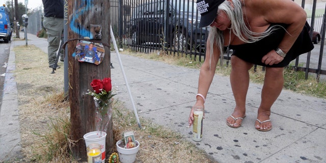 Maria Ramirez places a candle near a police involved shooting of a teen in Los Angeles on Wednesday, Aug. 10, 2016.