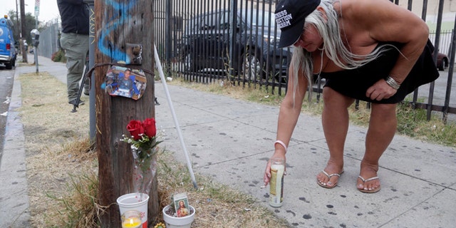 Maria Ramirez places a candle near a police involved shooting of a teen in Los Angeles on Wednesday, Aug. 10, 2016.