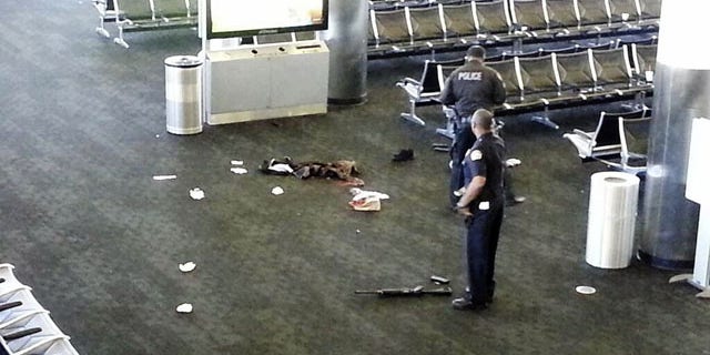 November 1, 2013: Police officers stand near a weapon at the Los Angeles International Airport after a gunman opened fire in the terminal, killing one person and wounding several others. (AP)
