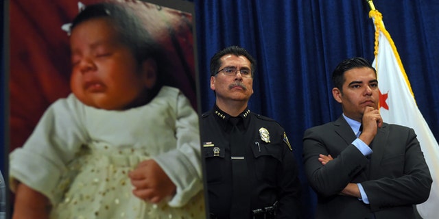 Long Beach Police Chief Robert Luna, left, and Mayor Robert Garcia stand during a news conference in Long Beach, Calif., Wednesday, March 25, 2015. Southern California authorities have arrested four people in a plot to kidnap two newborn babies. The plot ended with the death of a 3-week-old girl and the shooting and beating of the childrens mothers, police said Wednesday. At left is an image of baby Eliza Delacruz, who was snatched Jan. 3, 2015, in Long Beach by a gunman who wounded her parents and uncle, Luna said. Her body was found the next day in a trash bin near the Mexican border. (AP Photo/The Daily Breeze, Scott Varley)  MAGS OUT; NO SALES