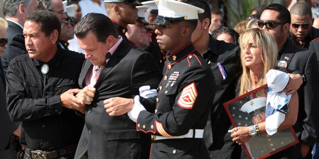 Aug. 18, 2012: Lance Cpl. Greg Buckley Jr.'s father Greg, foreground and mother Marina are escorted from St. Agnes Cathedral after his funeral Mass in Rockville Center, N.Y..