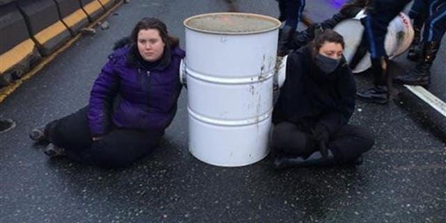 Protesters from the Boston contingent of Black Lives Matter sit near a barrel on Interstate 93 in Milton, Mass., on Jan. 15, 2015. (AP Photo/Massachusetts State Police)