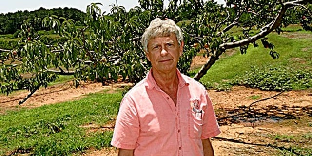 North Louisiana business owner Joe Mitcham stands in front of what’s left of his peach orchard, ravaged by a particular fungus. A product exists to fix the problem and save his business, but the federal government has phased it out of the market on the grounds that it threatens the ozone layer.