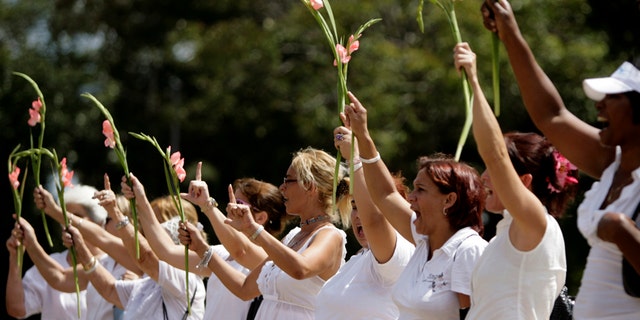 Members of the Ladies in White hold ups flowers as they demonstrate after their weekly march in Havana, Cuba, Sunday, March. 27, 2011. Ladies in White is a group of relatives of Cuban dissidents who were imprisoned. (AP Photo/Javier Galeano)