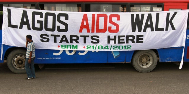 A man walks past a banner tied on a bus before the start of a charity walk on HIV/AIDS at the Ebute Mata district in Nigeria's commercial capital Lagos.