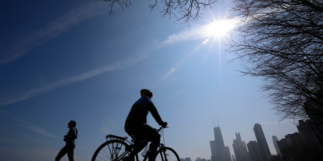 A jogger and a cyclist make their way around Lake Michigan in Chicago, March 21, 2014. (REUTERS/Jim Young)