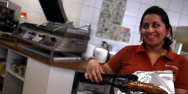 EAST HAVEN, CT - FEBRUARY 01: A waitress at Guti'z Bakery displays traditional Ecuadorian food on February 1, 2012 in East Haven, Connecticut. Following an investigation by the FBI, four East Haven police officers were arrested last week and accused of abusing Latinos in the working class community of 28,000 people which was nearly predominately white a generation ago. The case comes after a long and continuing FBI investigation where more arrests are expected. A recent civil rights investigation which was released last month revealed a pattern of discriminatory policing in East Haven and the town has been warned by the U.S. Justice Department to make reforms. The arrested officers have been accused of subjecting Hispanics to beatings and false arrests among other things. Currently East Haven's Latino population is around 10 percent. (Photo by Spencer Platt/Getty Images)