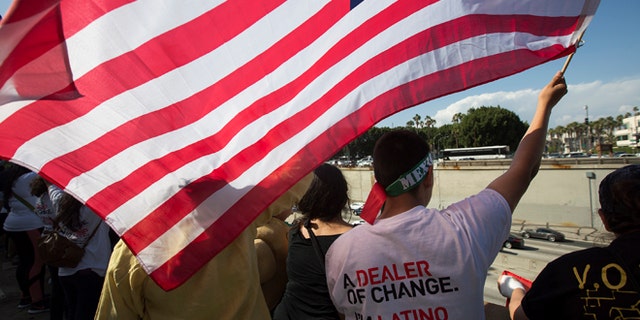 LOS ANGELES, CALIFORNIA - MAY 1: People wave flags and cheer over the 101 freeway near the Metropolitan Detention Center during one of several May Day marches on May 1, 2016 in Los Angeles, California. Immigrants, union members, workers and supporters are participating in the annual marches in downtown Los Angeles to call for greater rights for immigrants and improved conditions for workers. (Photo by David McNew/Getty Images)