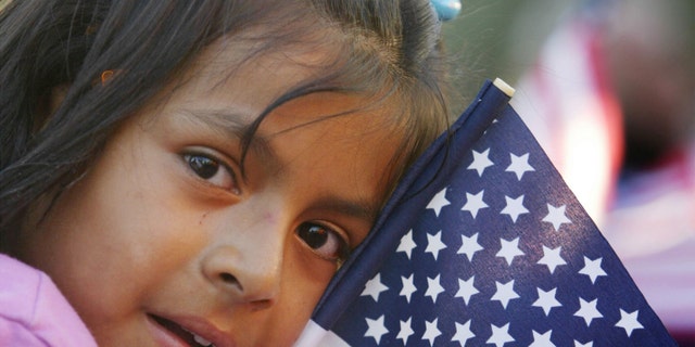 LOS ANGELES - SEPTEMBER 5: A Latina girl clutches an American flag while waiting to see California Governor Gray Davis sign the controversial SB 60 into law,, allowing undocumented immigrants to get a California driver's license September 5, 2003 in Los Angeles, California. Critics claim that Davis reversed his position on the bill to gain Latino votes in the October 7 recall election. (Photo by David McNew/Getty Images)