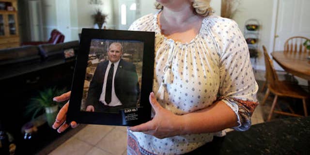 FILE - In this July 13, 2016 file photo, Laurie Holt holds a photograph of her son Josh Holt at her home, in Riverton, Utah. U.S. government officials and Holt, the mother of a Utah man jailed in Venezuela are worried about his deteriorating health. Josh Holt has been jailed since June 30 on suspicion of weapons charges. He traveled to Venezuela to marry a fellow Mormon he met online. His mother says he's innocent.  (AP Photo/Rick Bowmer, File)