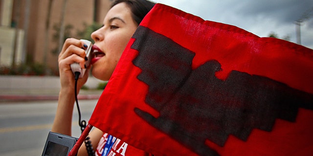 Yvette Salinas, with L.U.P.E chants "Education not Deportation" into a megaphone on Thursday, March, 19, 2015 outside of the federal courthouse in Brownsville, Texas. The Justice Department might face sanctions if a federal judge determines its attorneys misled him about whether part of President Barack Obama's executive action on immigration was implemented prior to it being put on hold by the judge. U.S. District Judge Andrew Hanen last month halted Obama's plan. The president's plan would spare from deportation up to 5 million people in the U.S. illegally. (AP Photo/The Brownsville Herald, Yvette Vela)