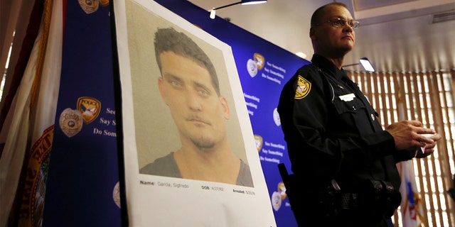 Tallahassee Police Department Public information officer David Northway reveals an image of Sigfredo Garcia, 34, during a press conference in Tallahassee, Fla., Thursday, May 26, 2016. Garcia is wanted for the murder of Florida State University law professor Dan Markel. Markel was killed in his Tallahassee home in July 2014. (Joe Rondone/Tallahassee Democrat via AP)