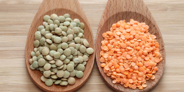 Green and red lentils in a wooden spoons. Close-up.