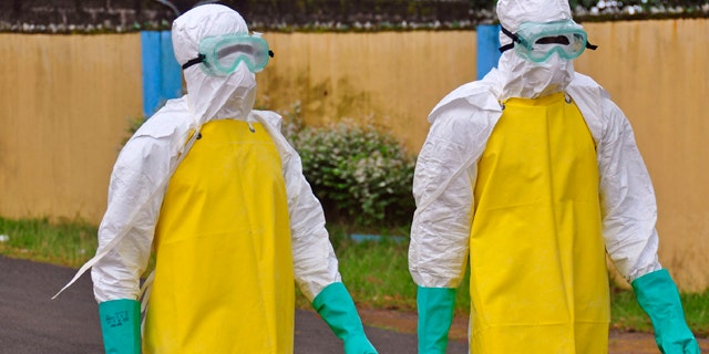 August 16, 2014: Health workers wearing protective gear go to remove the body of a person who is believed to have died after contracting the Ebola virus in the city of Monrovia, Liberia. (AP Photo/Abbas Dulleh)