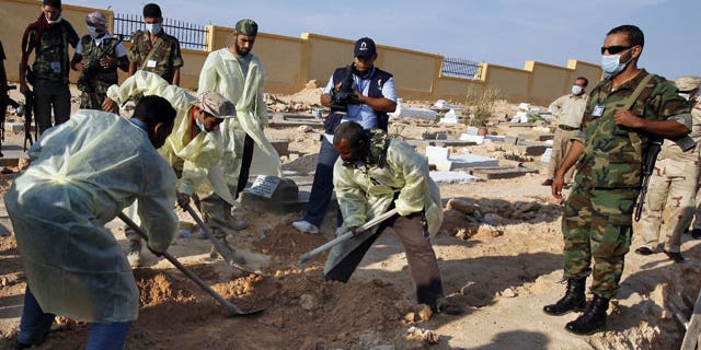 Libyan medical team and revolutionary fighters dig at a mass grave in Gargarish, on the coast some four miles, from the center of Tripoli, Libya, containing the bodies of more than 200 people who were killed in the chaos surrounding the rebel assault that ousted Muammar Qaddafi.