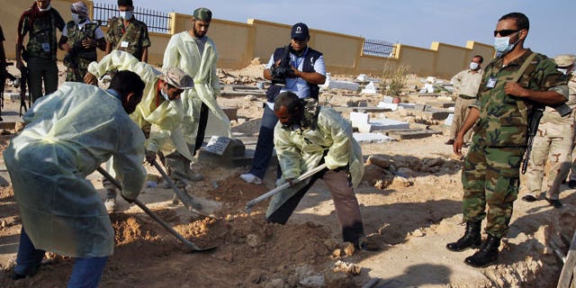 Libyan medical team and revolutionary fighters dig at a mass grave in Gargarish, on the coast some four miles, from the center of Tripoli, Libya, containing the bodies of more than 200 people who were killed in the chaos surrounding the rebel assault that ousted Muammar Qaddafi.