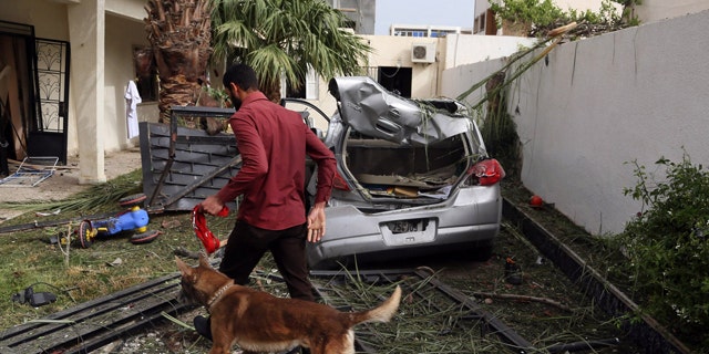 April 23, 2013: A security officer using a sniffer dog inspects the site of a car bomb that targeted the French embassy wounding two French guards and causing extensive material damage in Tripoli, Libya.