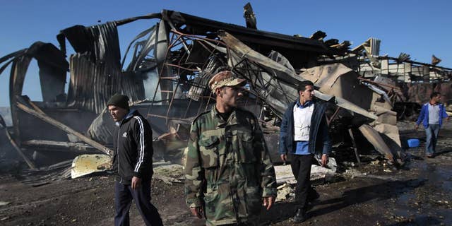 A Libyan soldier walks outside wreckage/AP Photo