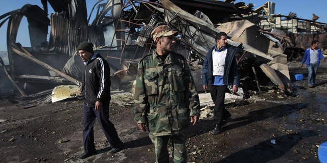 A Libyan soldier walks outside wreckage/AP Photo