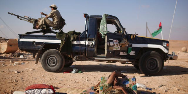 A former rebel fighter rests at the northern gate of Bani Walid, Libya, Saturday, Sept. 17, 2011. Revolutionary fighters struggled to regroup Saturday outside the loyalist stronghold of Bani Walid after being driven back by fierce resistance from followers of Muammar Qaddafi, temporarily quieting one battlefield.