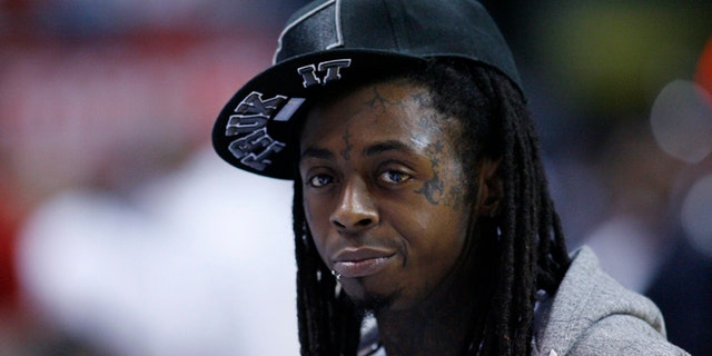 Rapper Lil' Wayne looks from courtside during game between the Indiana Pacers and the Miami Heat
during Game 2 of their NBA Eastern Conference second round basketball playoff series in Miami, Florida May 15, 2012. REUTERS/Andrew Innerarity (UNITED STATES - Tags: SPORT BASKETBALL) - RTR324GJ