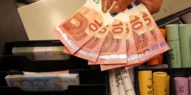 FILE - A Thursday, Jan. 1, 2015 photo from files showing euro coins and banknotes shown by a salesclerk at a shop in Vilnius, Lithuania. Europe’s struggle with economic stagnation is raising questions about whether its prized project _ the shared euro currency _ can bounce back or even just survive. Fundamental gaps left at the euro’s creation in 1999 are haunting its policymakers. The euro’s missing pieces have come into sharper focus as the European Central Bank prepares to decide Thursday, Jan. 22, 2015, whether more monetary stimulus is needed to ward off crippling deflation and as Greece faces a Sunday election that could conceivably lead to its leaving the 19-nation eurozone. (AP Photo/Mindaugas Kulbis, File)