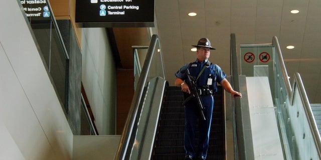 BOSTON - AUGUST 10: A Massachusetts State Police officer rides an escalator at Logan International Airport August 10, 2006 in Boston, Massachusetts. The Department of Homeland Security raised the terrorism alert to Red, the highest level, for commercial flights from Britain to the United States after an alleged terrorist plot to blow up planes was disrupted by British authorities. (Photo by Darren McCollester/Getty Images)